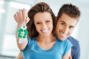 Young couple holding out keys to a new home